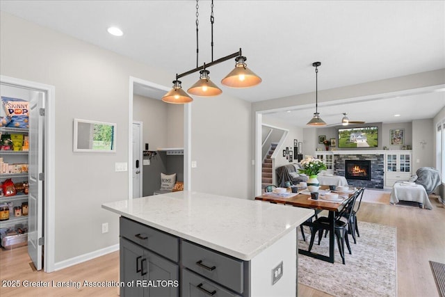 4150 Stillbrook Ln, Dewitt, MI 48820 - kitchen with gray cabinets, light wood-style floors, a fireplace, hanging light fixtures, and recessed lighting