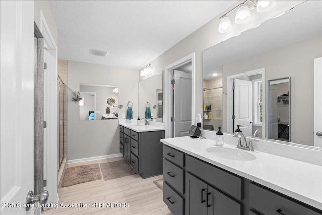 4150 Stillbrook Ln, Dewitt, MI 48820 - full bath featuring a stall shower, two vanities, a walk in closet, and wood finished floors