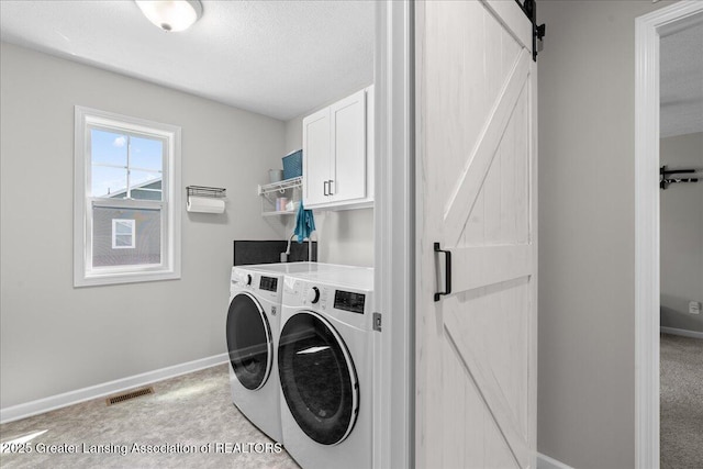 4150 Stillbrook Ln, Dewitt, MI 48820 - laundry area featuring washing machine and clothes dryer, a barn door, cabinet space, baseboards, and a textured ceiling