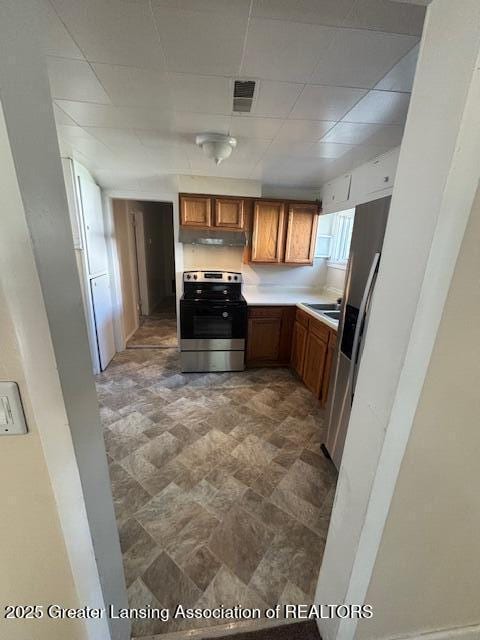 107 Cox Blvd, Lansing, MI 48910 - kitchen with electric stove, under cabinet range hood, light countertops, brown cabinetry, and a drop ceiling