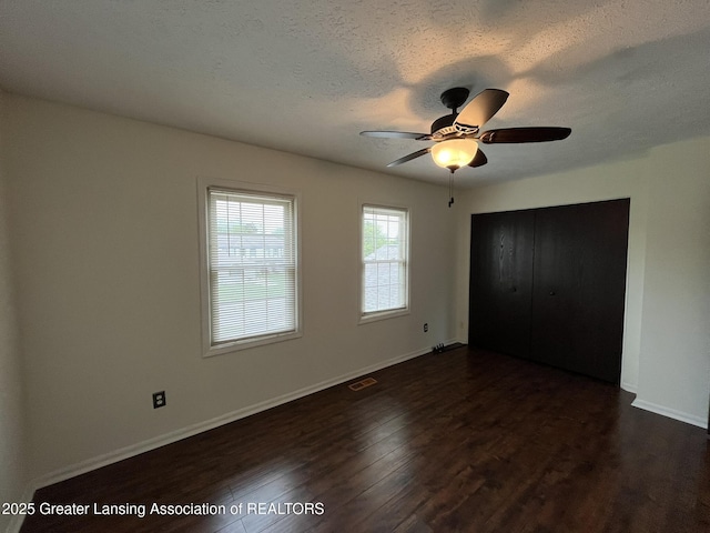7436 Creekside Dr Unit 10, Lansing, MI 48917 - unfurnished bedroom with a textured ceiling, dark wood-style floors, baseboards, and a ceiling fan