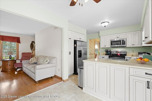 3720 Lott Ave, Holt, MI 48842 - kitchen with appliances with stainless steel finishes, light countertops, ceiling fan, white cabinetry, and a peninsula