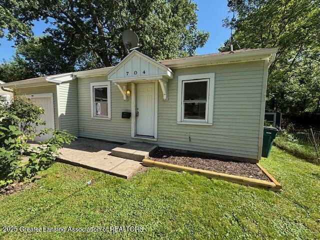 704 Mckim Ave, Lansing, MI 48910 - bungalow-style home featuring a front yard and a garage
