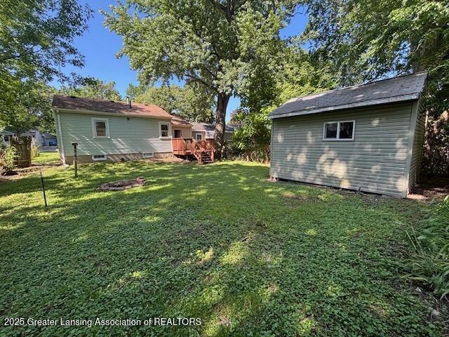 704 Mckim Ave, Lansing, MI 48910 - view of grassy yard with a deck and a storage shed