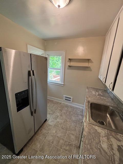 704 Mckim Ave, Lansing, MI 48910 - kitchen with stainless steel fridge with ice dispenser and white cabinetry