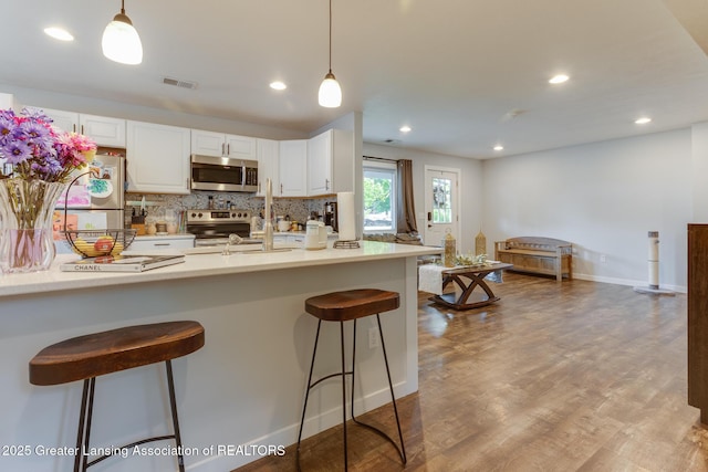 4614 Addison Rd, Lansing, MI 48917 - kitchen featuring appliances with stainless steel finishes, white cabinetry, tasteful backsplash, decorative light fixtures, and recessed lighting