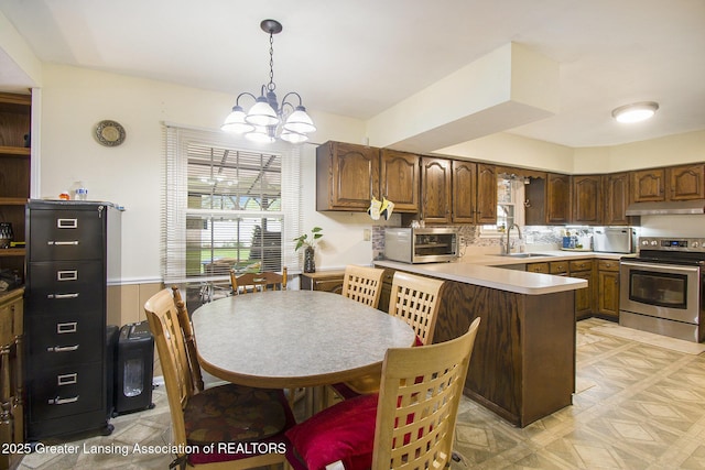 3733 Colchester Rd, Lansing, MI 48906 - kitchen with stainless steel range with electric stovetop, under cabinet range hood, a sink, a peninsula, and a chandelier