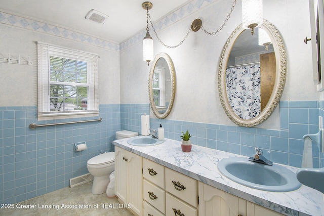 3733 Colchester Rd, Lansing, MI 48906 - bathroom with tile walls, double vanity, toilet, wainscoting, and tile patterned floors