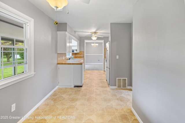 1111 Battle Creek Rd, Charlotte, MI 48813 - kitchen featuring a ceiling fan, white cabinetry, a sink, and baseboards