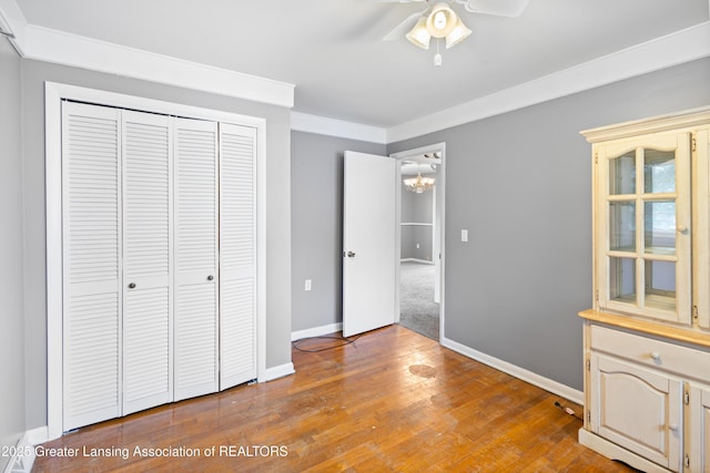 1111 Battle Creek Rd, Charlotte, MI 48813 - unfurnished bedroom featuring baseboards, a closet, wood-type flooring, a chandelier, and ornamental molding