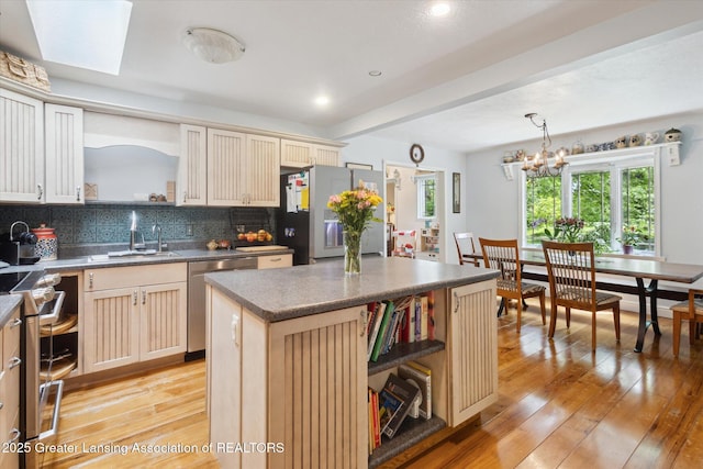 1435 Epley Rd, Williamston, MI 48895 - kitchen with open shelves, cream cabinetry, appliances with stainless steel finishes, a sink, and light wood finished floors