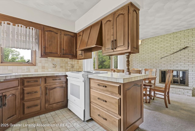 847 N Waverly Rd, Dimondale, MI 48821 - kitchen featuring white electric stove, custom range hood, tile countertops, brown cabinets, and tasteful backsplash