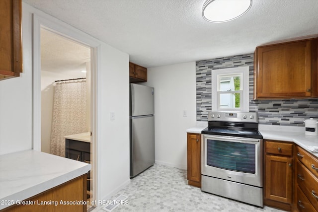 1900 Kaplan St, Lansing, MI 48917 - kitchen with stainless steel appliances, brown cabinets, a textured ceiling, light countertops, and decorative backsplash