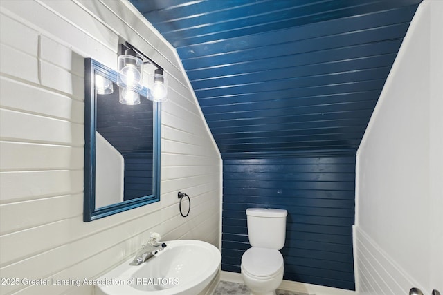 1900 Kaplan St, Lansing, MI 48917 - half bath featuring a sink, toilet, wood walls, and vaulted ceiling