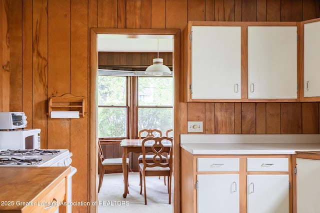 3129 Birch Row Dr, East Lansing, MI 48823 - kitchen featuring wooden walls, light countertops, white cabinetry, white microwave, and carpet floors