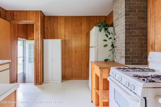 3129 Birch Row Dr, East Lansing, MI 48823 - kitchen featuring white gas range oven, light countertops, wooden walls, and brown cabinetry
