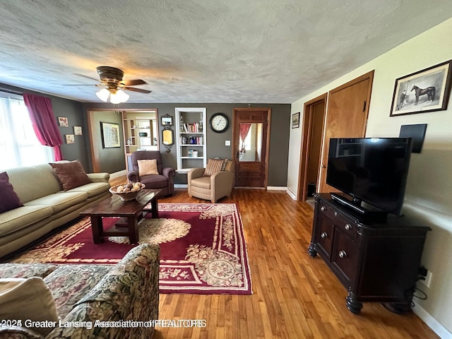 13862 Hartel Rd, Grand Ledge, MI 48837 - living area with light wood-type flooring, ceiling fan, baseboards, built in features, and a textured ceiling