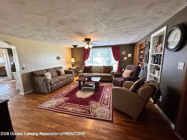13862 Hartel Rd, Grand Ledge, MI 48837 - living area with arched walkways, a textured ceiling, wood finished floors, ceiling fan, and baseboards