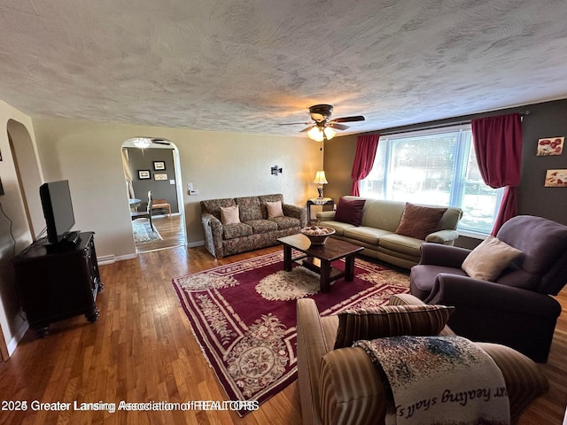 13862 Hartel Rd, Grand Ledge, MI 48837 - living area with arched walkways, ceiling fan, a textured ceiling, hardwood / wood-style floors, and baseboards