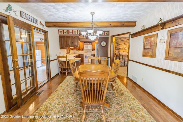 2278 Narrow Lake Rd, Charlotte, MI 48813 - dining room featuring french doors, beamed ceiling, a chandelier, wood finished floors, and wallpapered walls