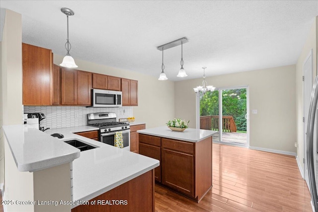 4026 Watts Ln, Lansing, MI 48911 - kitchen featuring appliances with stainless steel finishes, brown cabinets, light countertops, backsplash, and a textured ceiling