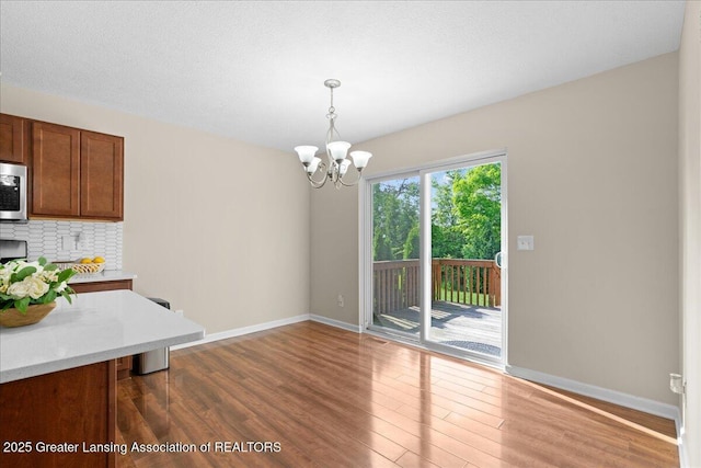4026 Watts Ln, Lansing, MI 48911 - unfurnished dining area with a chandelier, wood finished floors, and baseboards
