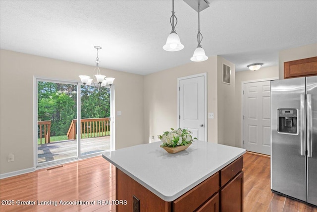 4026 Watts Ln, Lansing, MI 48911 - kitchen with stainless steel refrigerator with ice dispenser, a chandelier, light wood-style flooring, a center island, and light countertops