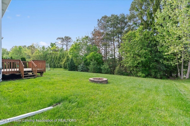 4026 Watts Ln, Lansing, MI 48911 - view of green lawn with an outdoor fire pit, a deck, and view of scattered trees