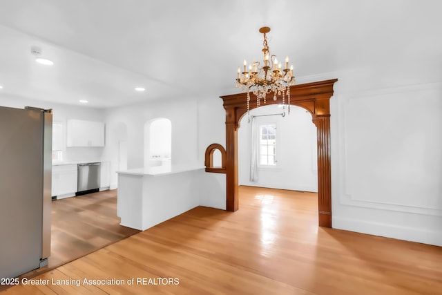 414 W St, Lansing, MI 48915 - unfurnished dining area featuring light wood-style flooring, a chandelier, recessed lighting, and arched walkways
