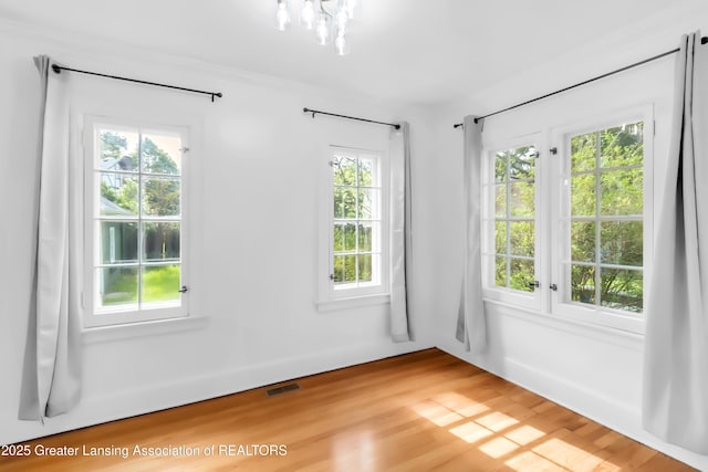 414 W St, Lansing, MI 48915 - empty room featuring plenty of natural light, light wood-type flooring, and a chandelier