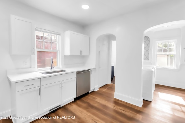 414 W St, Lansing, MI 48915 - kitchen featuring stainless steel dishwasher, a sink, arched walkways, white cabinetry, and light countertops