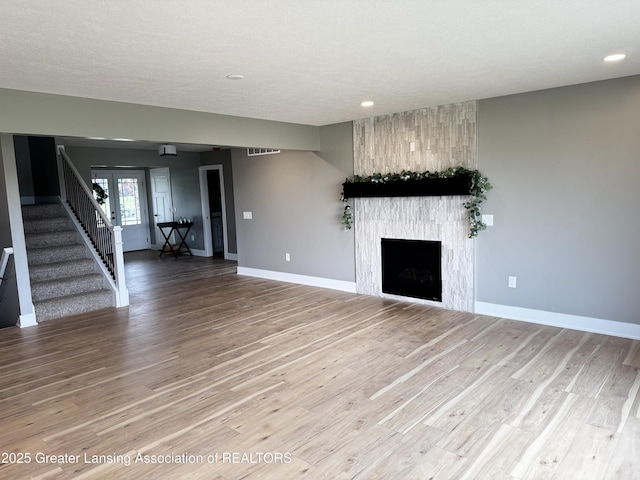 9135 Klein Farm, Grand Ledge, MI 48837 - unfurnished living room with stairs, baseboards, wood finished floors, recessed lighting, and a large fireplace