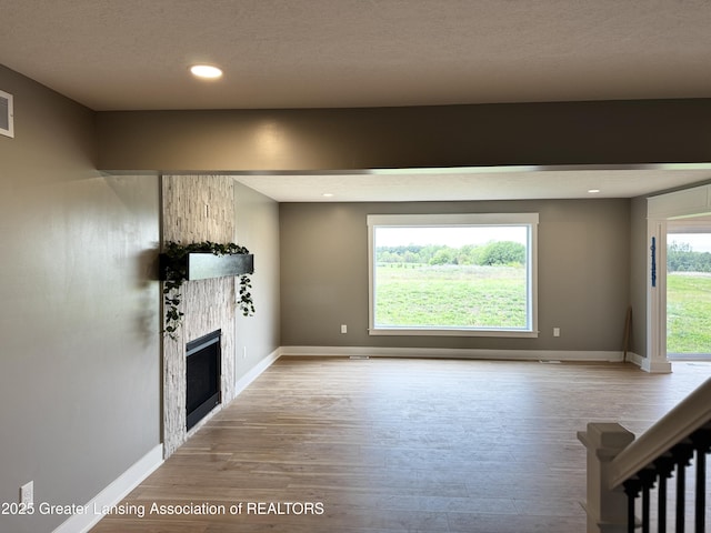 9135 Klein Farm, Grand Ledge, MI 48837 - unfurnished living room with wood finished floors, a large fireplace, baseboards, recessed lighting, and a textured ceiling