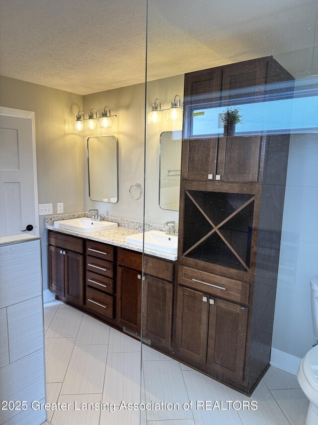 9135 Klein Farm, Grand Ledge, MI 48837 - bathroom with toilet, double vanity, a textured ceiling, tile patterned floors, and baseboards