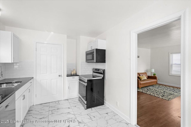 1200 W Rundle Ave, Lansing, MI 48910 - kitchen with appliances with stainless steel finishes, a sink, dark countertops, and light marble finish floors