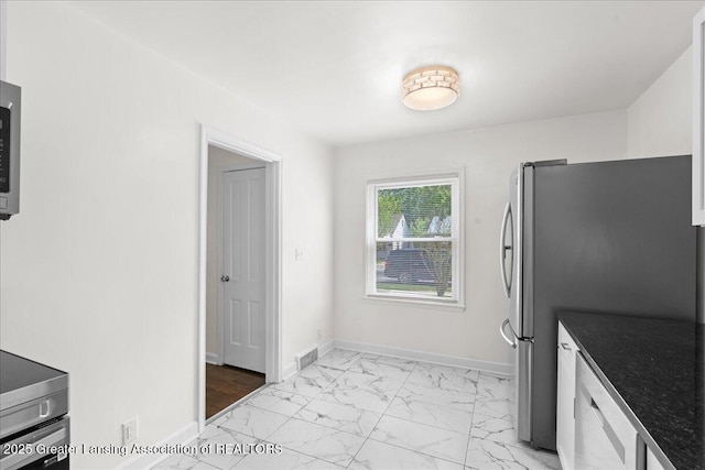 1200 W Rundle Ave, Lansing, MI 48910 - kitchen featuring light marble finish flooring, freestanding refrigerator, and baseboards