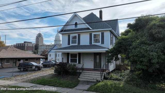 411 W Ionia St, Lansing, MI 48933 - american foursquare style home featuring covered porch, a chimney, and roof with shingles