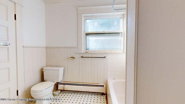 411 W Ionia St, Lansing, MI 48933 - bathroom with a baseboard heating unit, toilet, a bathtub, wainscoting, and tile patterned floors