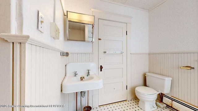 411 W Ionia St, Lansing, MI 48933 - bathroom featuring baseboard heating, toilet, a wainscoted wall, and tile patterned floors