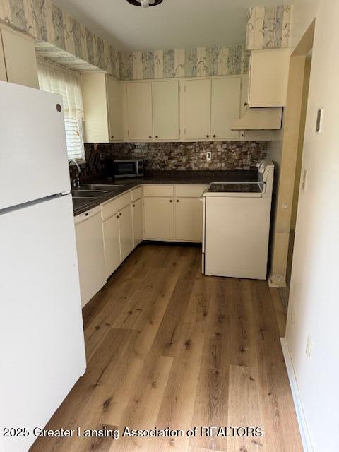 956 Trafalger Ln, East Lansing, MI 48823 - kitchen with white appliances, decorative backsplash, premium range hood, light wood-type flooring, and dark countertops