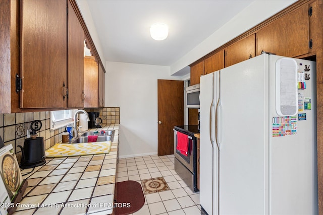 1416 Briarwood Dr, Lansing, MI 48917 - kitchen featuring freestanding refrigerator, a sink, decorative backsplash, stainless steel range with electric cooktop, and tile counters