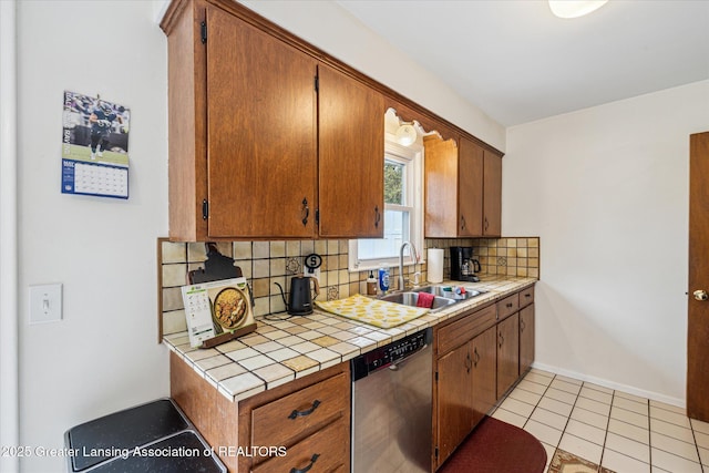 1416 Briarwood Dr, Lansing, MI 48917 - kitchen with stainless steel dishwasher, a sink, tasteful backsplash, tile counters, and baseboards
