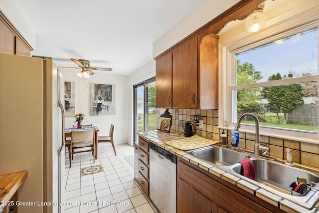 1416 Briarwood Dr, Lansing, MI 48917 - kitchen with freestanding refrigerator, dishwasher, tile countertops, a sink, and tasteful backsplash