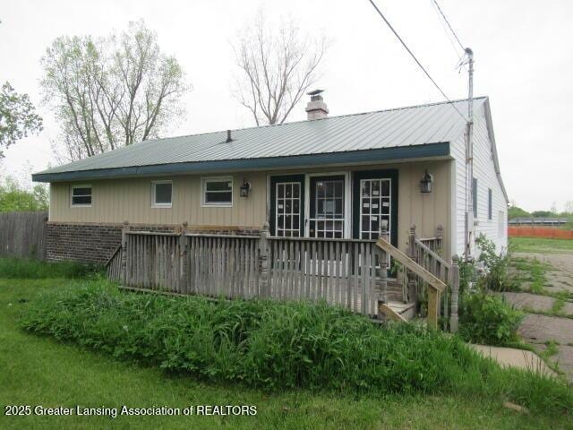 2071 Vandekarr Rd, Owosso, MI 48867 - rear view of house featuring a deck, metal roof, and a chimney