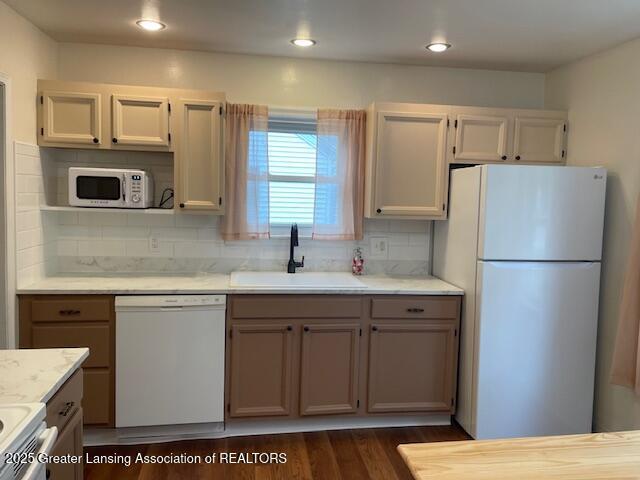 2303 Devonshire Ave, Lansing, MI 48910 - kitchen with white appliances, a sink, backsplash, dark wood-type flooring, and recessed lighting