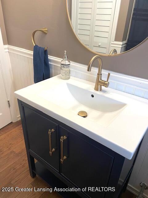 2303 Devonshire Ave, Lansing, MI 48910 - bathroom featuring a wainscoted wall, wood finished floors, and vanity