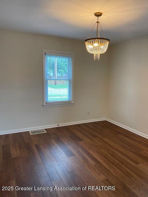 2303 Devonshire Ave, Lansing, MI 48910 - spare room featuring a chandelier, baseboards, and dark wood-style flooring