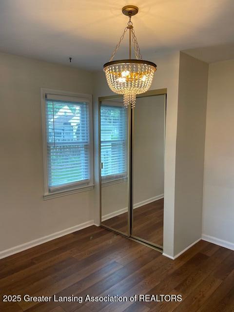 2303 Devonshire Ave, Lansing, MI 48910 - unfurnished dining area featuring a chandelier, wood finished floors, and baseboards