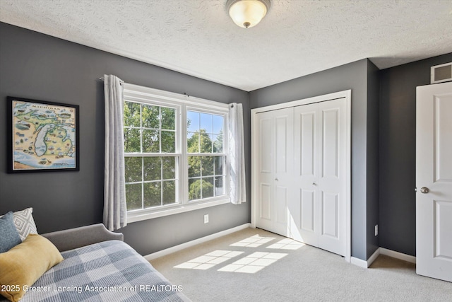 3893 E Plover Pl, East Lansing, MI 48823 - bedroom featuring baseboards, carpet floors, a closet, and a textured ceiling