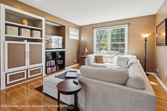 3893 E Plover Pl, East Lansing, MI 48823 - living area featuring wood finished floors, baseboards, and a textured ceiling